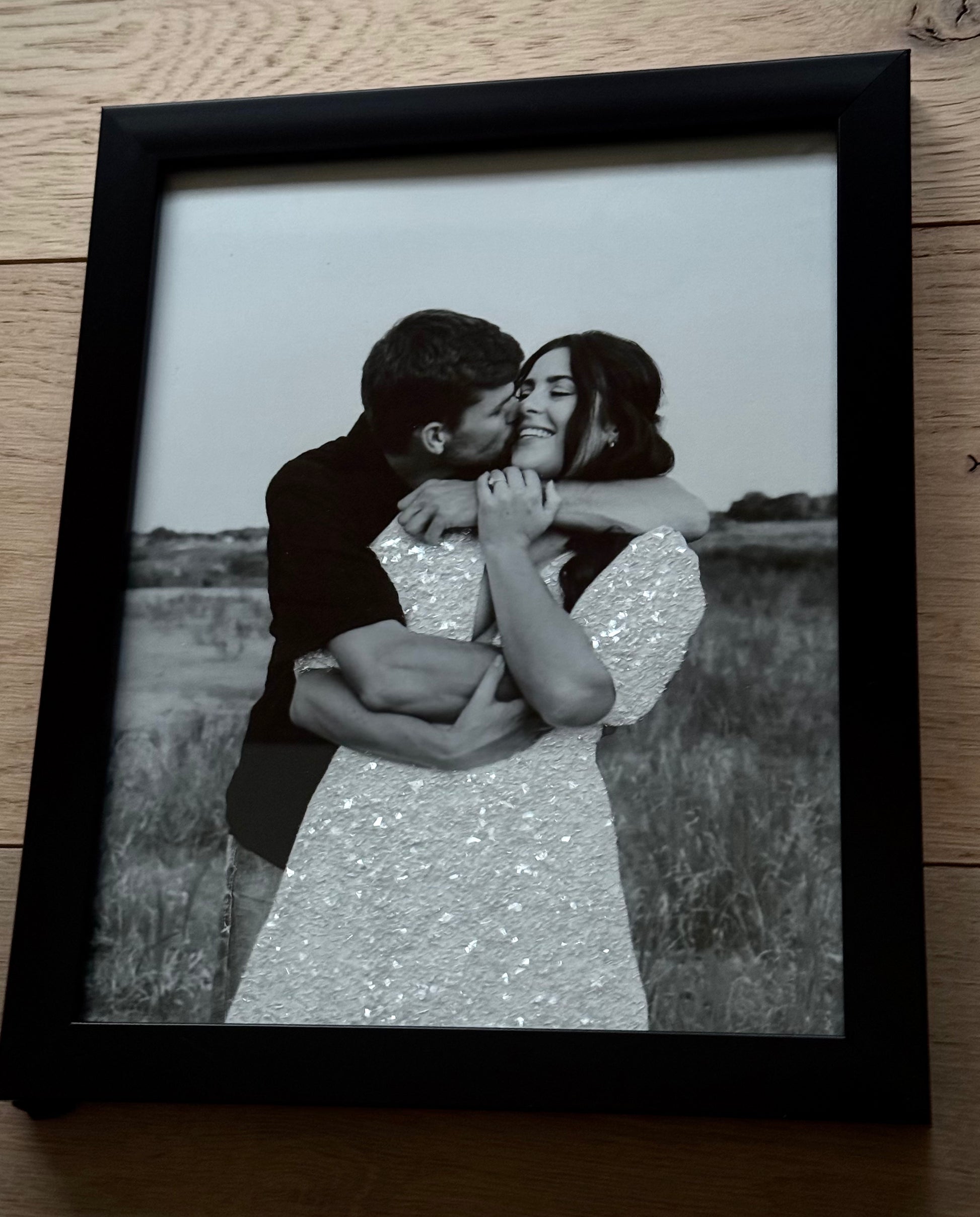 A sample of an engaged couple where bride's white dress is sparkle bedazzled, posed with an embrace in a field. 