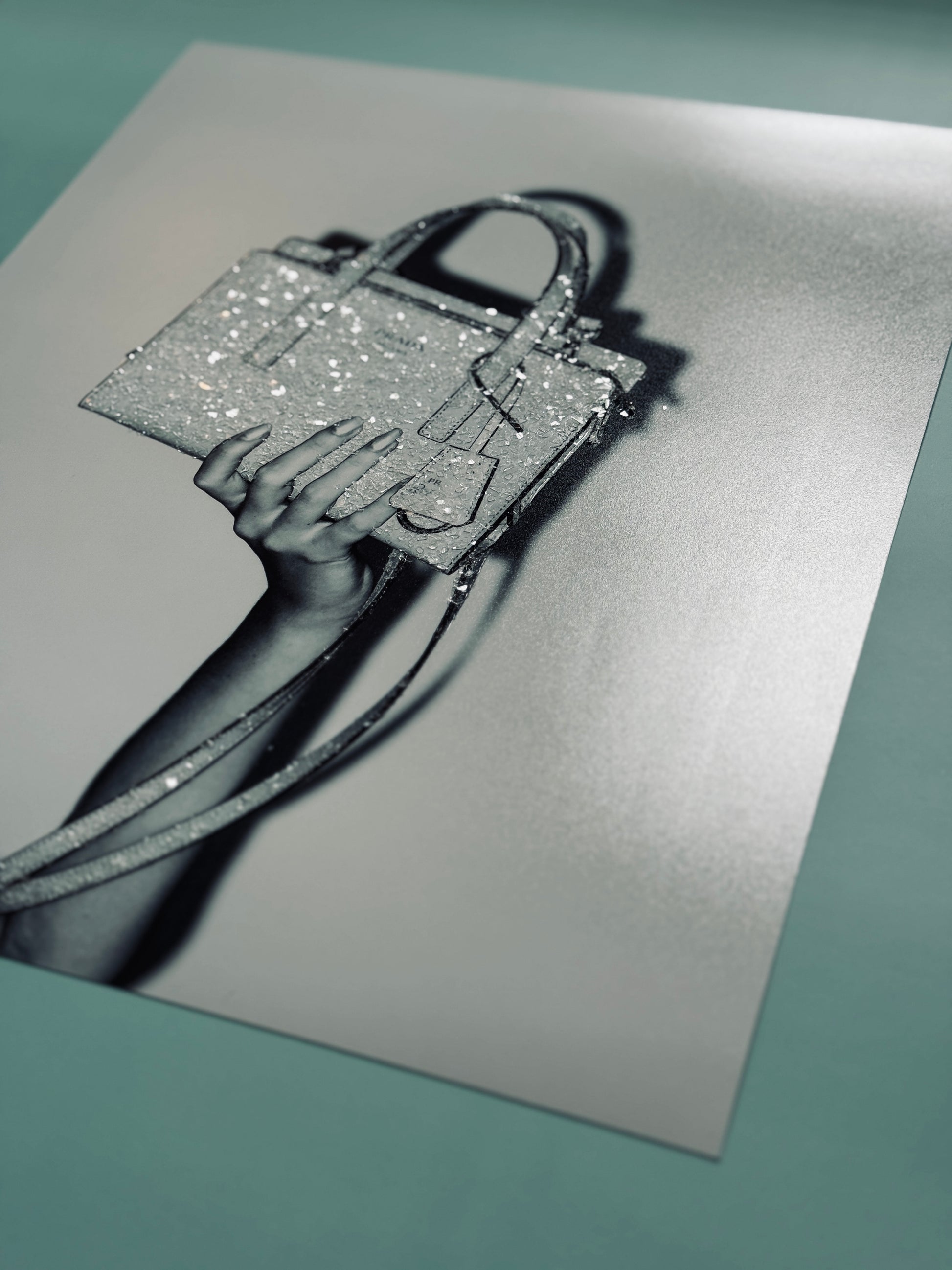 Bedazzled sparkle photograph of manicured hand holding black and white Prada handbag 