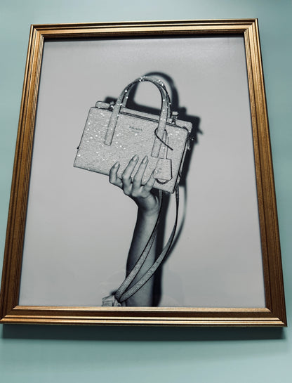 A photograph of a manicured hand holding a sparkle bedazzled Prada handbag.